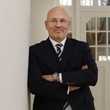 Matthias Grimm lehnt an einer Wand und lächelt freundlich