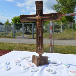 Ein Kreuz mit Namen auf weißen Steinen, die an verstorbene Wegbegleiter erinnern